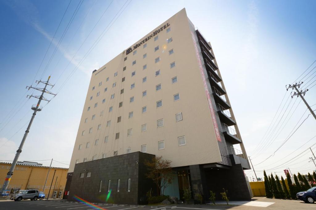 een groot wit gebouw met veel ramen bij Montein Hotel in Kitakami