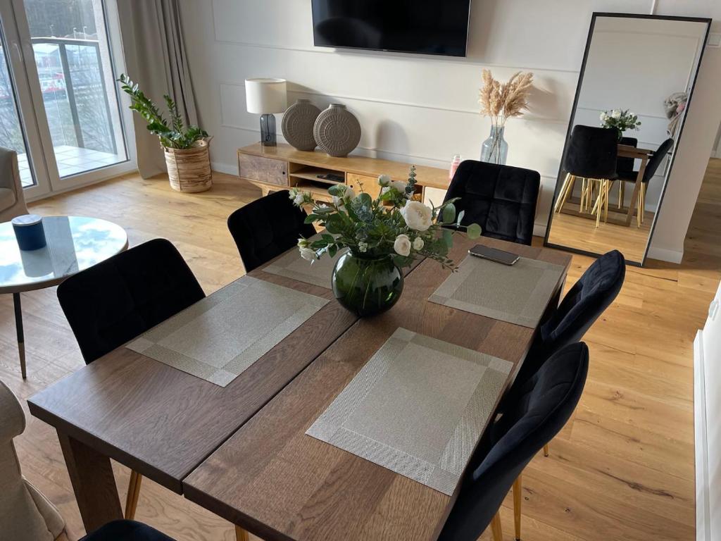 a dining room table with a vase of flowers on it at Sucha Street Apartments, Nowa Letnica,Gdańsk in Gdańsk