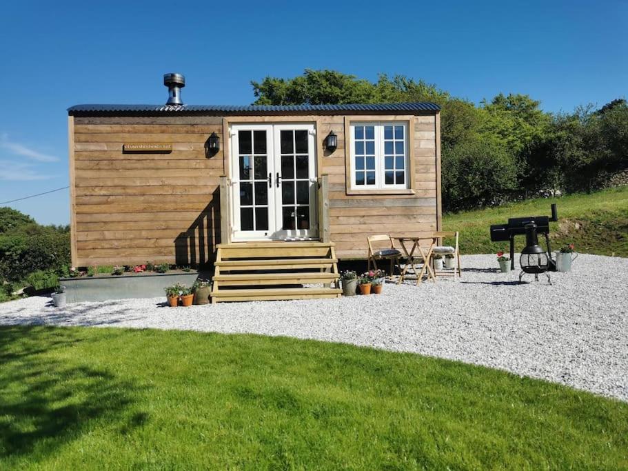 ein winziges Haus mit einer Veranda und einem Rasen in der Unterkunft Elvan Farm Shepherd's Hut in Exeter