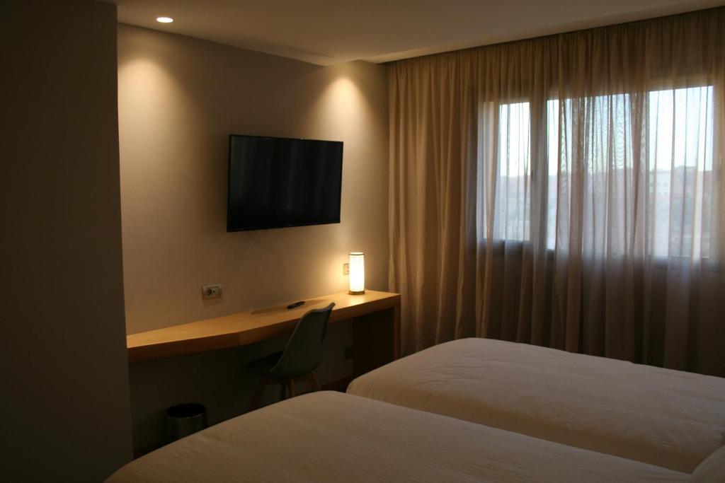 a hotel room with two beds and a desk with a television at Valley Boutique Hotel in Safi