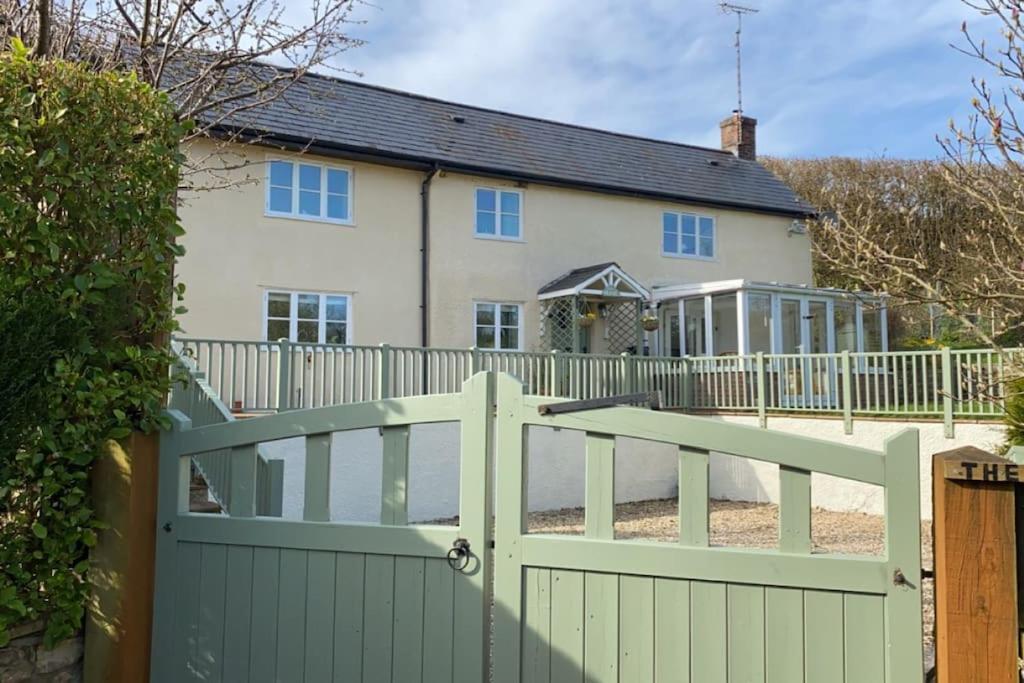 a white fence with a gate in front of a house at ‘The Nest’ A beautiful cottage in Devon in Axminster