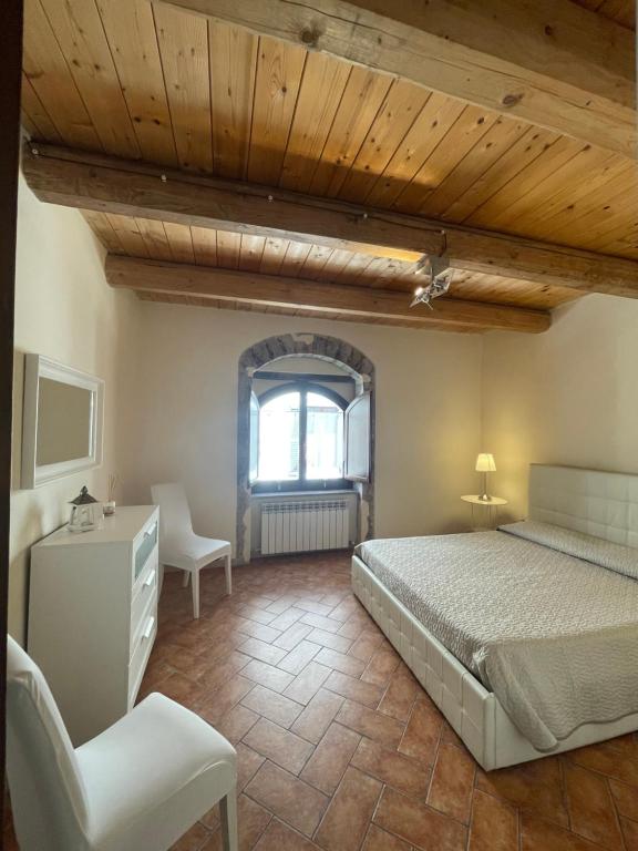 1 dormitorio con 1 cama, 1 silla y 1 ventana en Il Borghetto Medievale suite, en Fabriano