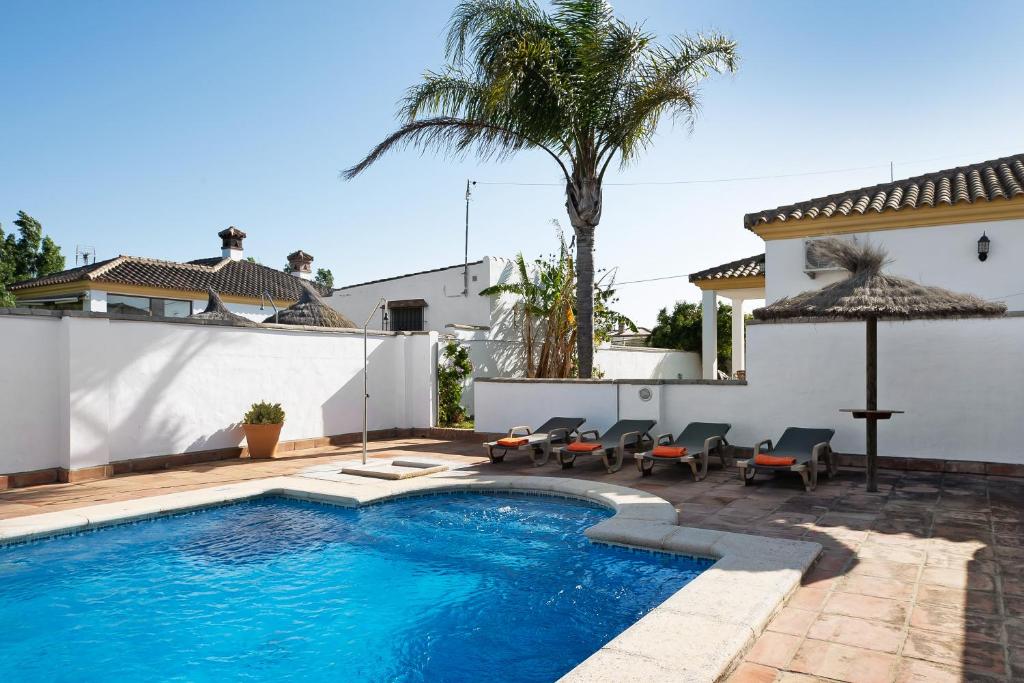 a swimming pool with chairs and an umbrella next to a house at Casa Villanueva 4 - Sólo Familias in Hozanejos
