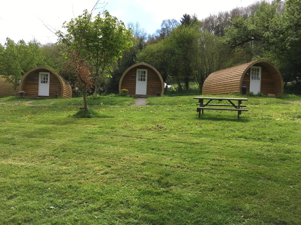 a picnic table in a field with two huts at Caplor Glamping & Lodges in Hereford