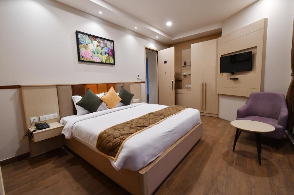 ein Hotelzimmer mit einem Bett und einem TV in der Unterkunft Soho Boutique Hotel in Mysore