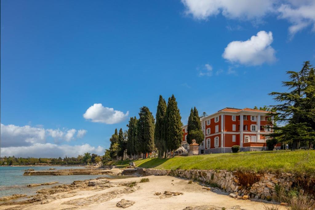a large red house on the shore of a river at Villa Valdepian Apartments in Savudrija