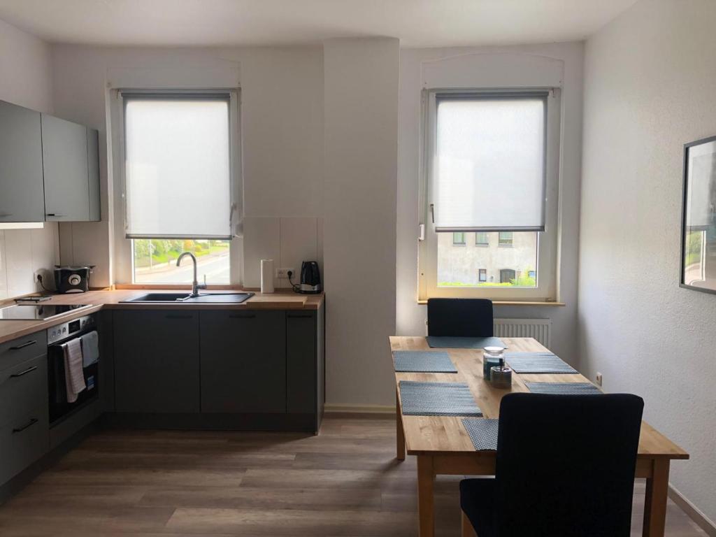 a kitchen with a wooden table and two windows at Pension Highway Bünde Hansastraße in Bünde