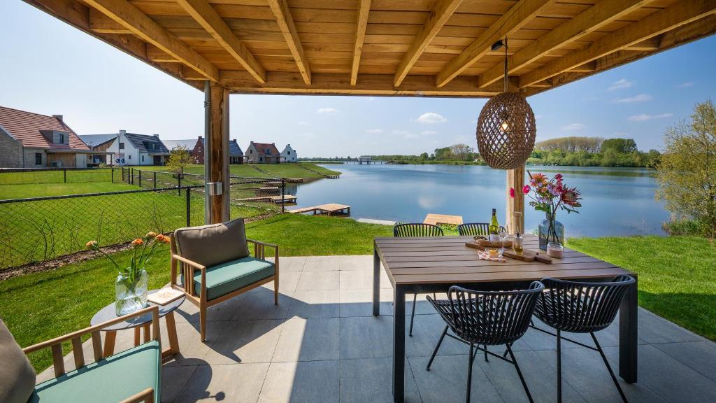 un patio con mesa y sillas y vistas al lago en Parc Maasresidence Thorn en Thorn