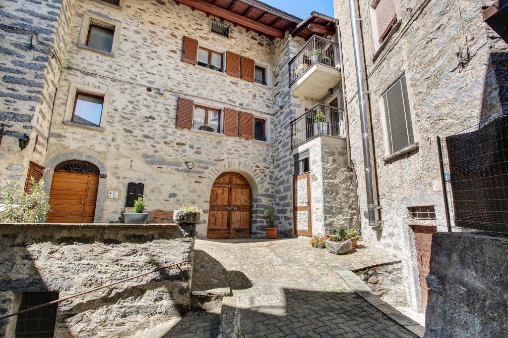 um grande edifício de pedra com uma porta de madeira em La Maison du Bonheur Grosio em Grosio