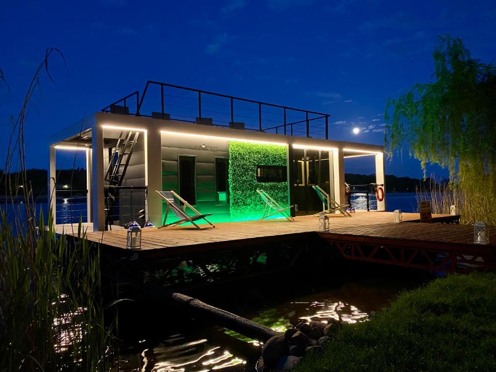 ein Haus auf einem Dock mit grüner Fassade in der Unterkunft AquaHouse Zamkowe in Wąbrzeźno