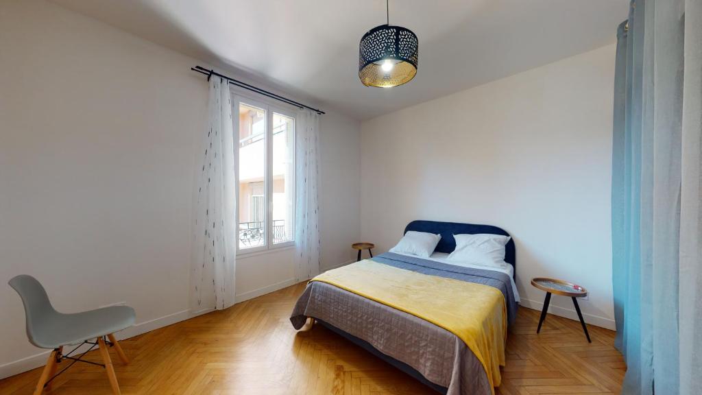 une chambre avec un lit, une chaise et une fenêtre dans l'établissement Grand appartement Fontana, à Nice