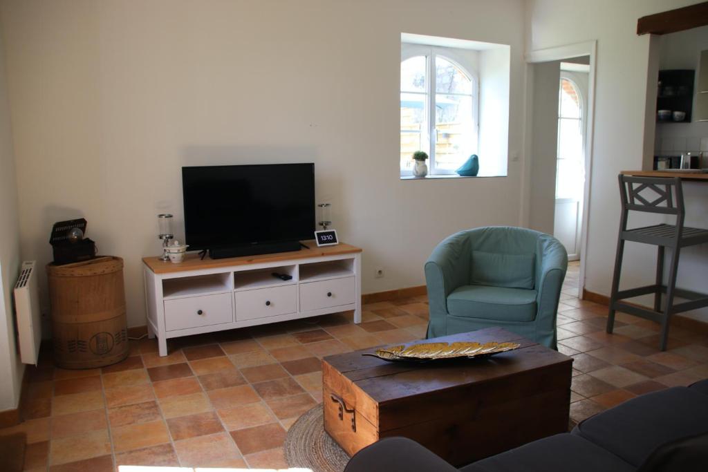 a living room with a flat screen tv and a chair at Le Vieil Home, au pied de la cité médiévale in La Haute-Chapelle