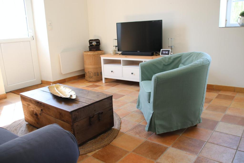 a living room with a tv and a chair and a table at Le Vieil Home, au pied de la cité médiévale in La Haute-Chapelle