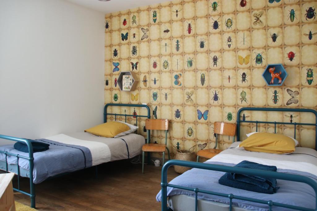 two beds in a room with a wall covered with a curtain at Le Vieil Home, au pied de la cité médiévale in La Haute-Chapelle
