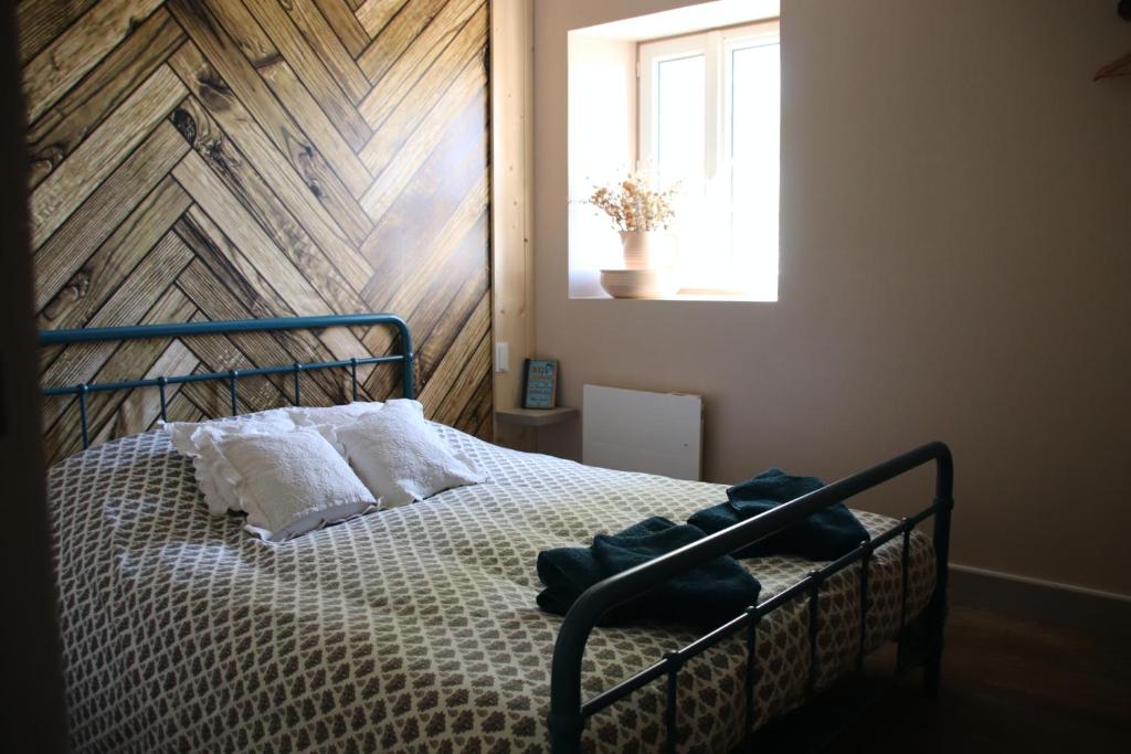 a bedroom with a bed with a wooden wall at Le Vieil Home, au pied de la cité médiévale in La Haute-Chapelle