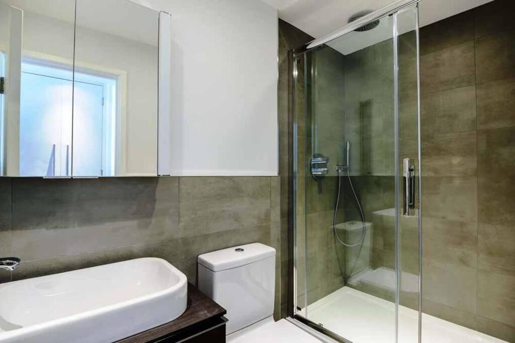 a bathroom with a shower and a toilet and a sink at Canal-Side Boutique Apartment in London