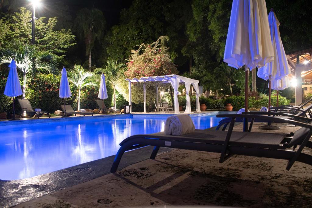 a pool with umbrellas and a table and chairs at Auberge Villa Cana in Cap-Haïtien