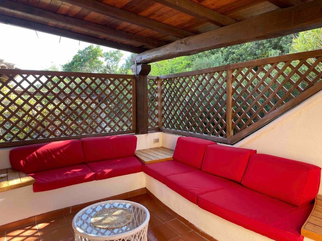 a porch with a red couch on a balcony at SAN TEODORO PUNTA EST CURATISSIMO BILOCALe in Capo Coda Cavallo