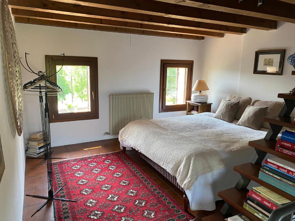 Colline di Luce في San Pietro di Feletto: غرفة نوم بسرير كبير وسجادة حمراء
