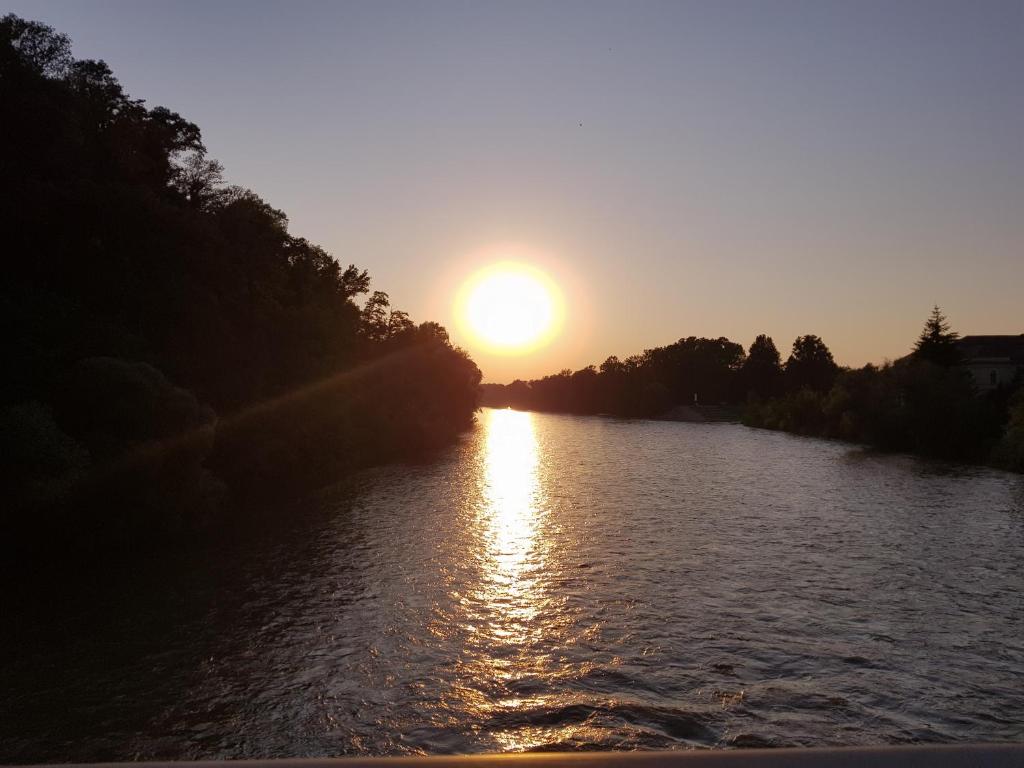 a sunset on a river with the sun setting at Fado Apartments Gornja Radgona in Gornja Radgona