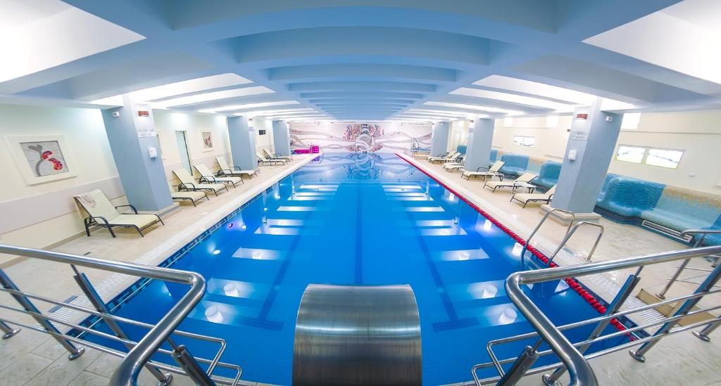 a large swimming pool in a building with chairs at Unirea Hotel & Spa in Iaşi