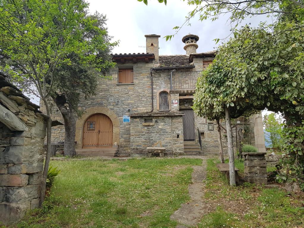 une vieille maison en pierre avec une porte en bois dans une cour dans l'établissement Casa Martín, à Guaso