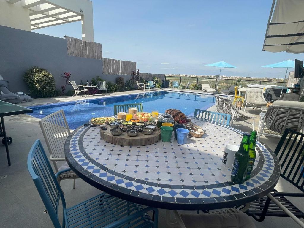 una mesa con una bebida junto a una piscina en צדפת המדבר en Giv'ot Bar