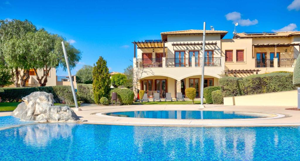 una casa con piscina di fronte a una casa di Pool side ground floor apartment BF02 - Theseus Village, Aphrodite Hills Resort a Kouklia