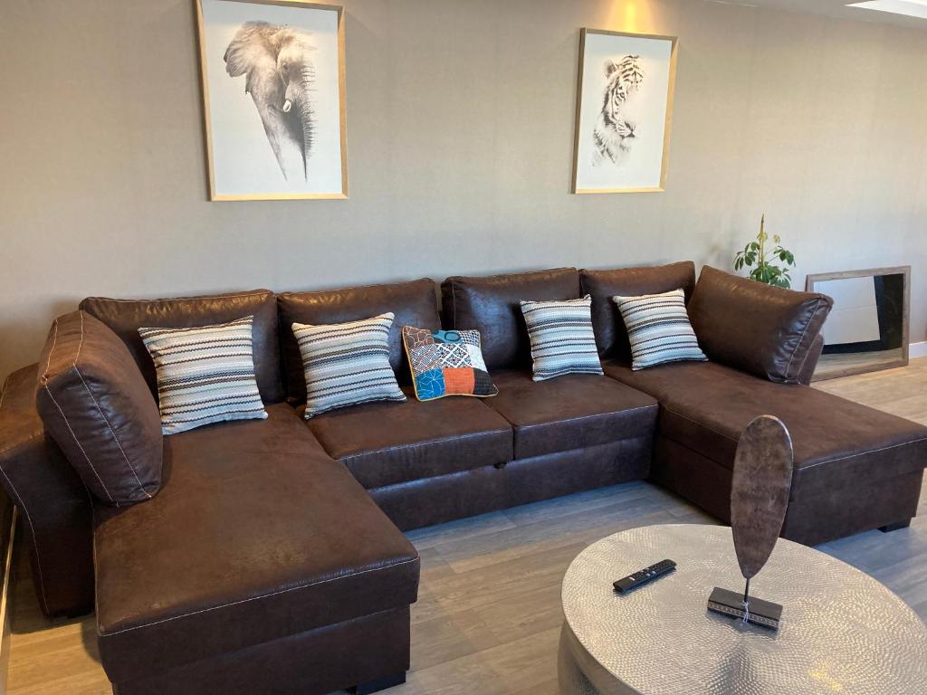 a brown leather couch in a living room with a table at Nouveau !! Bel appartement à Fécamp tout près de la plage, gare et voie verte in Fécamp