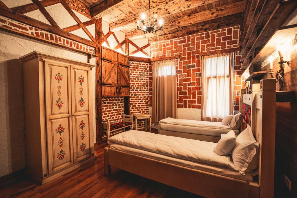 1 dormitorio con 2 camas y pared de ladrillo en Conacul Sfântul Sava Brancovici en Ineu