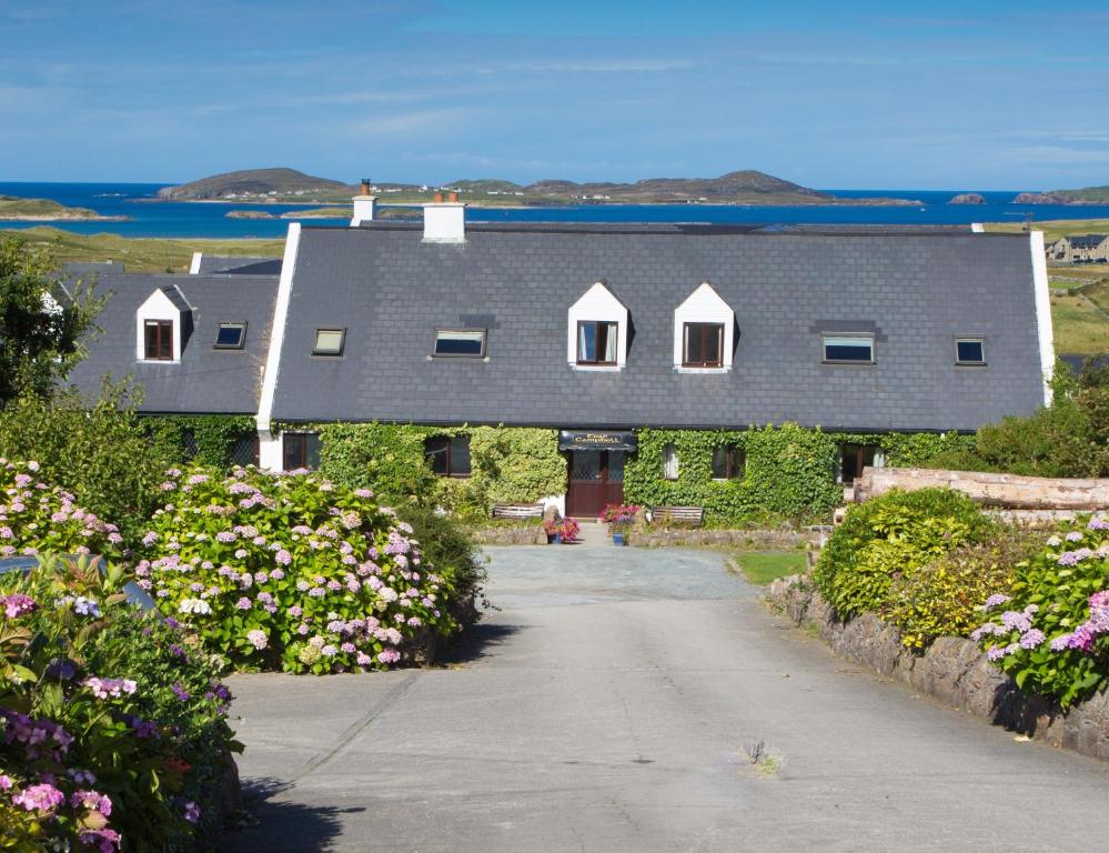 ein Haus mit einer Einfahrt und Blumen davor in der Unterkunft Teac Campbell Guesthouse in Bunbeg