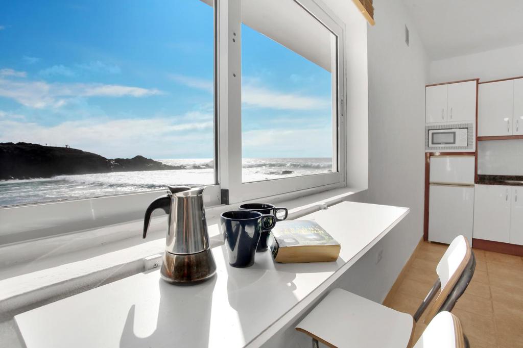 a kitchen with a window and a table with a book at Apartamentos Marinera I y II in El Cotillo