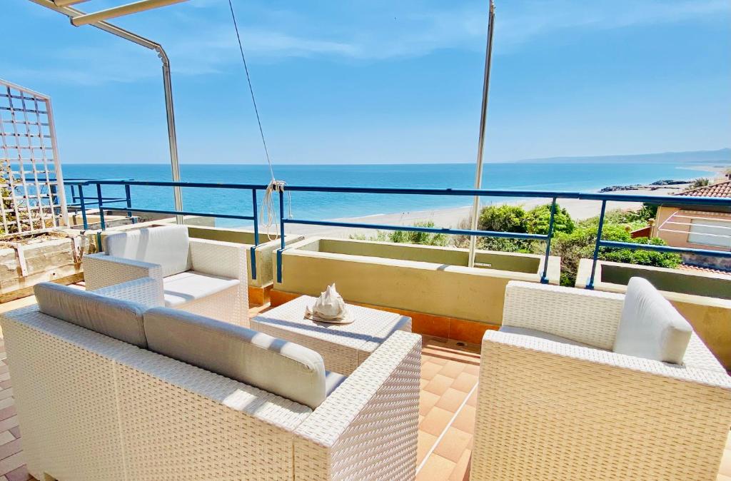 a balcony with white chairs and a view of the ocean at The Dream - Seafront Loft in Giardini Naxos