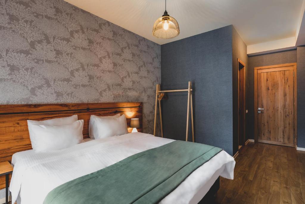una camera da letto con un letto grande con testiera in legno di Hotel Stancia Kazbegi - City Center a Kazbegi