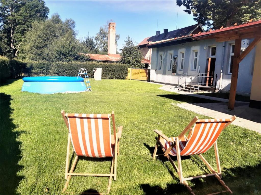 dos sillas sentadas en el césped junto a una piscina en Ubytování BRLOH Sedloňov v Orlických horách, en Sedloňov