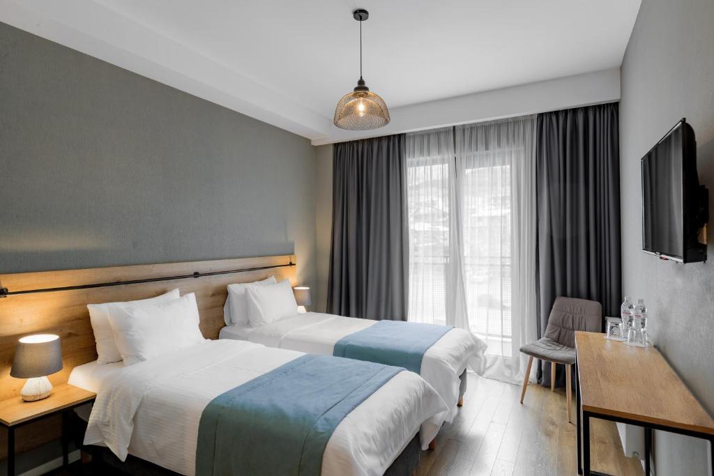 una camera d'albergo con due letti e una finestra di Hotel Stancia Kazbegi - City Center a Kazbegi