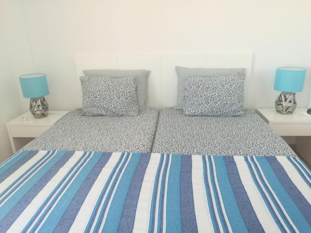 a bedroom with two twin beds with blue pillows at Casa ao Mar in Monte Gordo