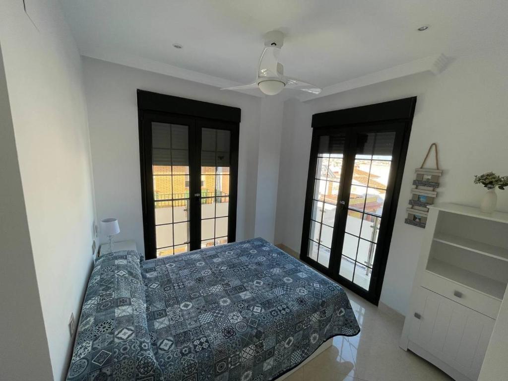 um quarto com uma cama e duas janelas em Vivienda Turística Playa Vida Punta Umbría em Punta Umbría