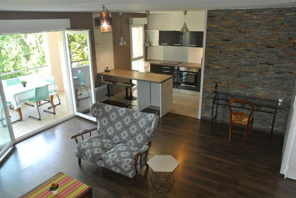 ein Wohnzimmer mit einem Sofa und einem Stuhl sowie eine Küche in der Unterkunft beau t3 en duplex, calme et paisible in Bayonne