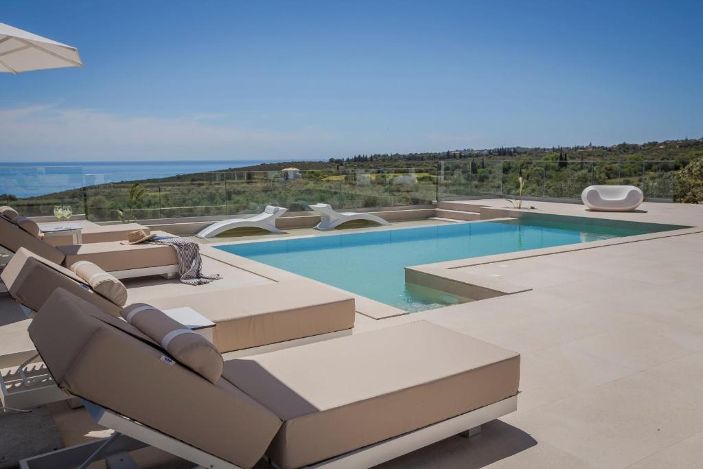 a swimming pool with lounge chairs and the ocean at Olea O' Luxury Living in Pesádha