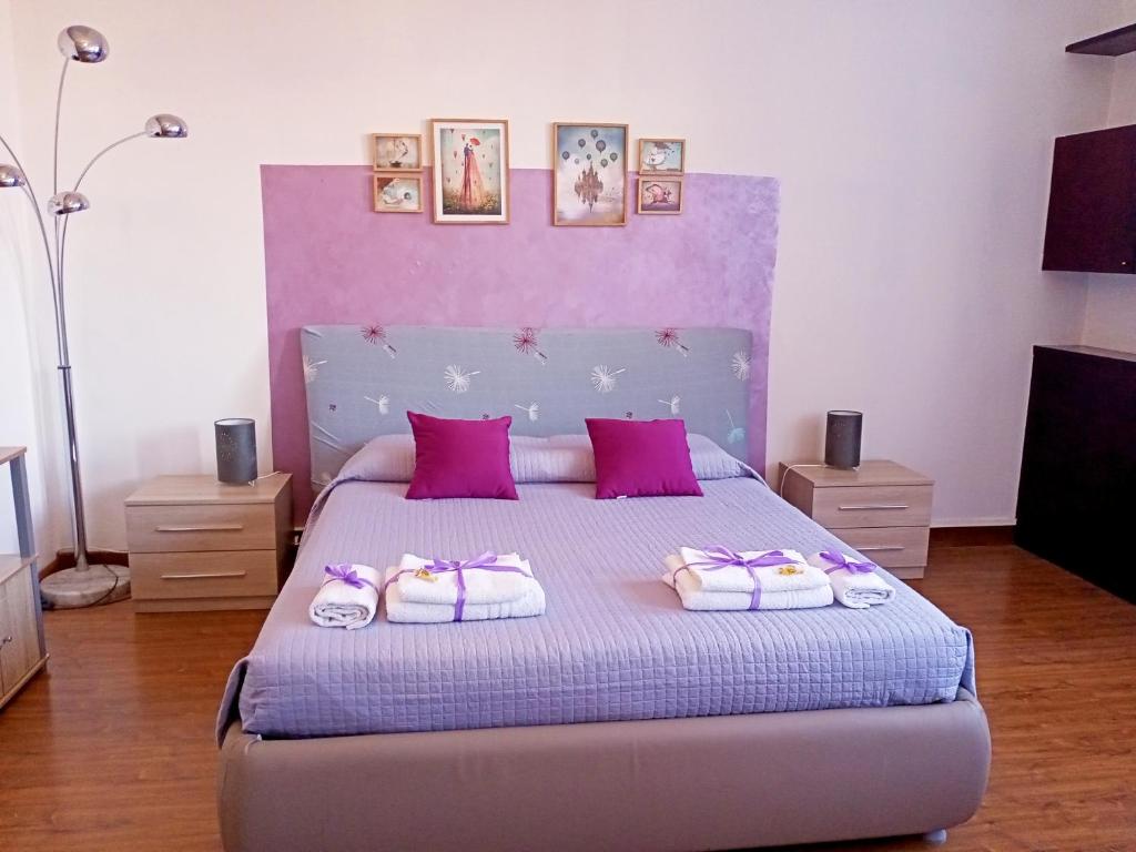 a bedroom with a bed with purple and pink pillows at Brà Guest House in Verona