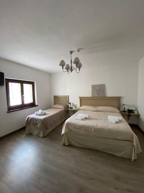 sypialnia z 2 łóżkami, oknem i żyrandolem w obiekcie HOTEL CAMPO STELLA w mieście Leonessa