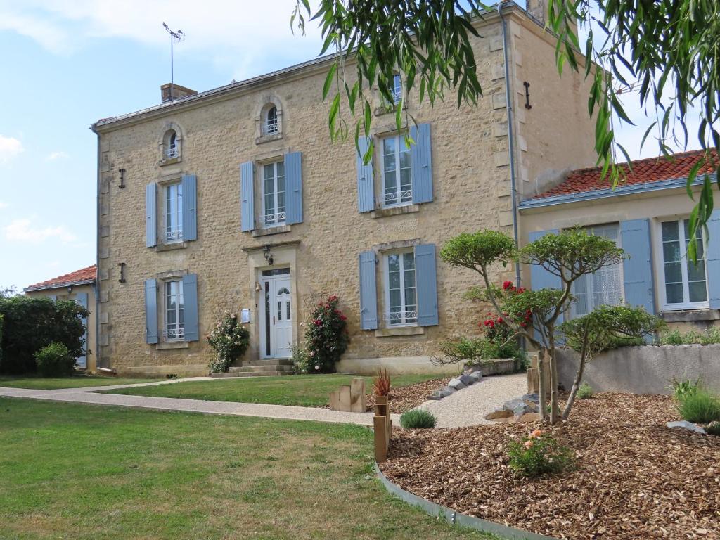 ein altes Steinhaus mit blauen Fensterläden in der Unterkunft Chambres d'Hôtes Le Tilleul in Saint-Hilaire-des-Loges