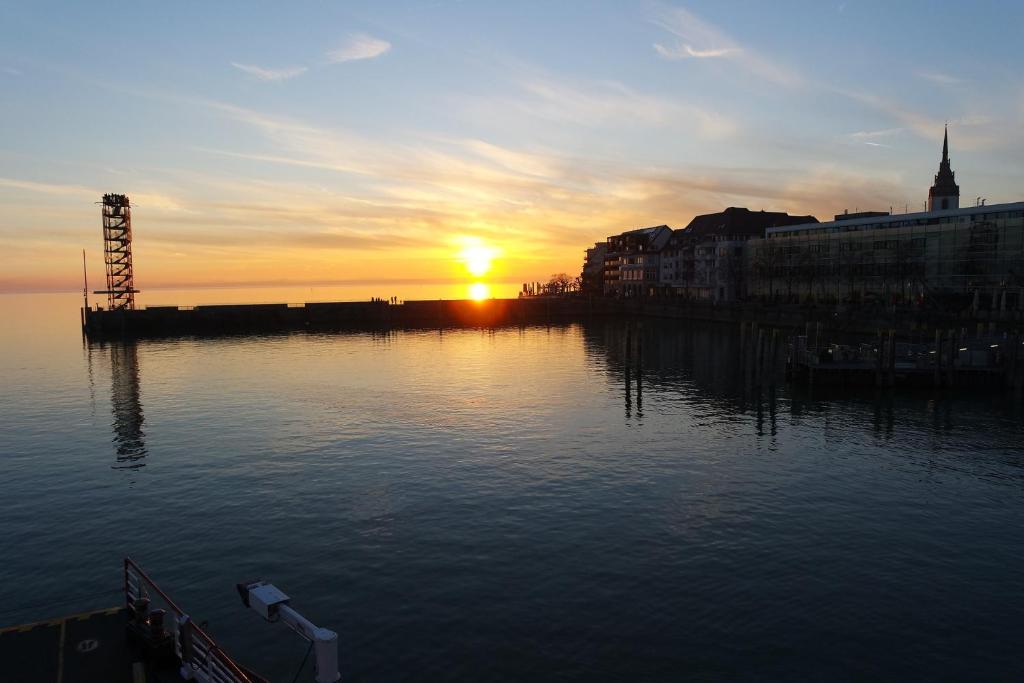 a sunset over a body of water with the sun setting at Apartment "SUN" in Friedrichshafen