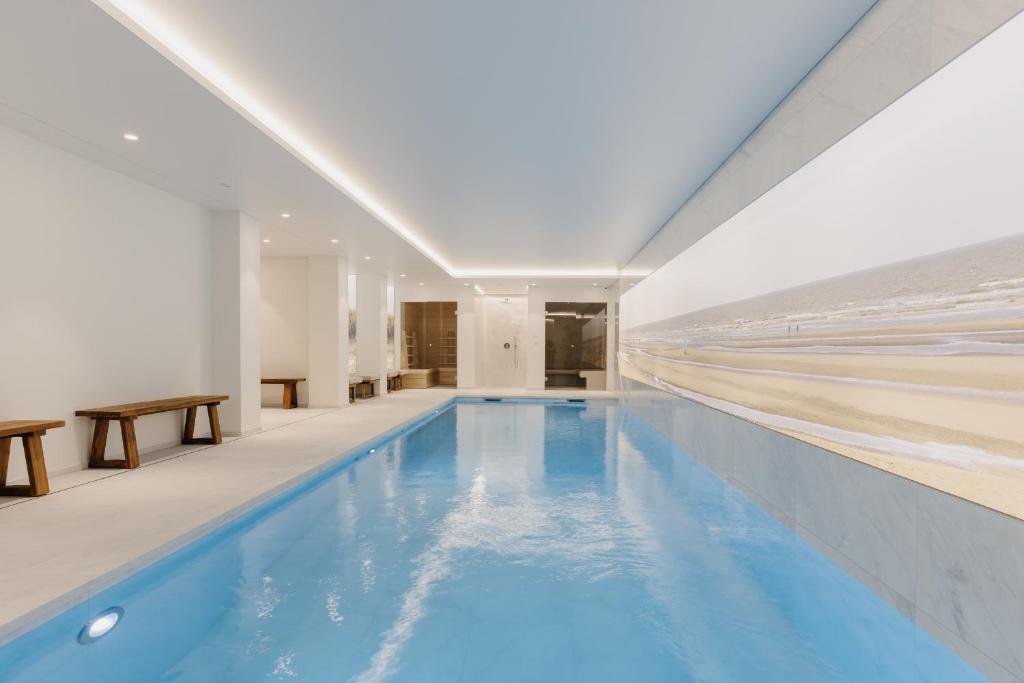 a swimming pool with blue water in a building at Portwin luxury stays in Knokke-Heist