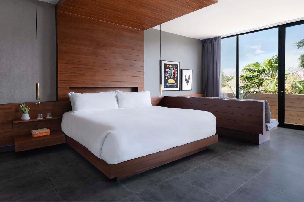 a bedroom with a large bed and a large window at MARQUEE Playa Hotel in Playa del Carmen