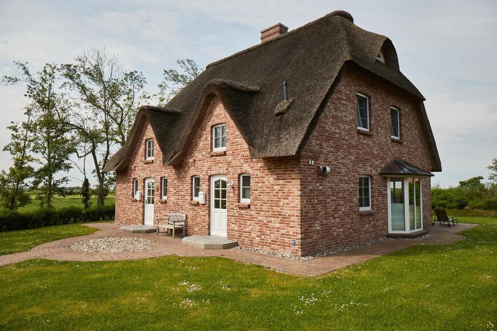 a large brick house with a thatched roof at Beach House Reetdachhaus Beach House 1 in Tating