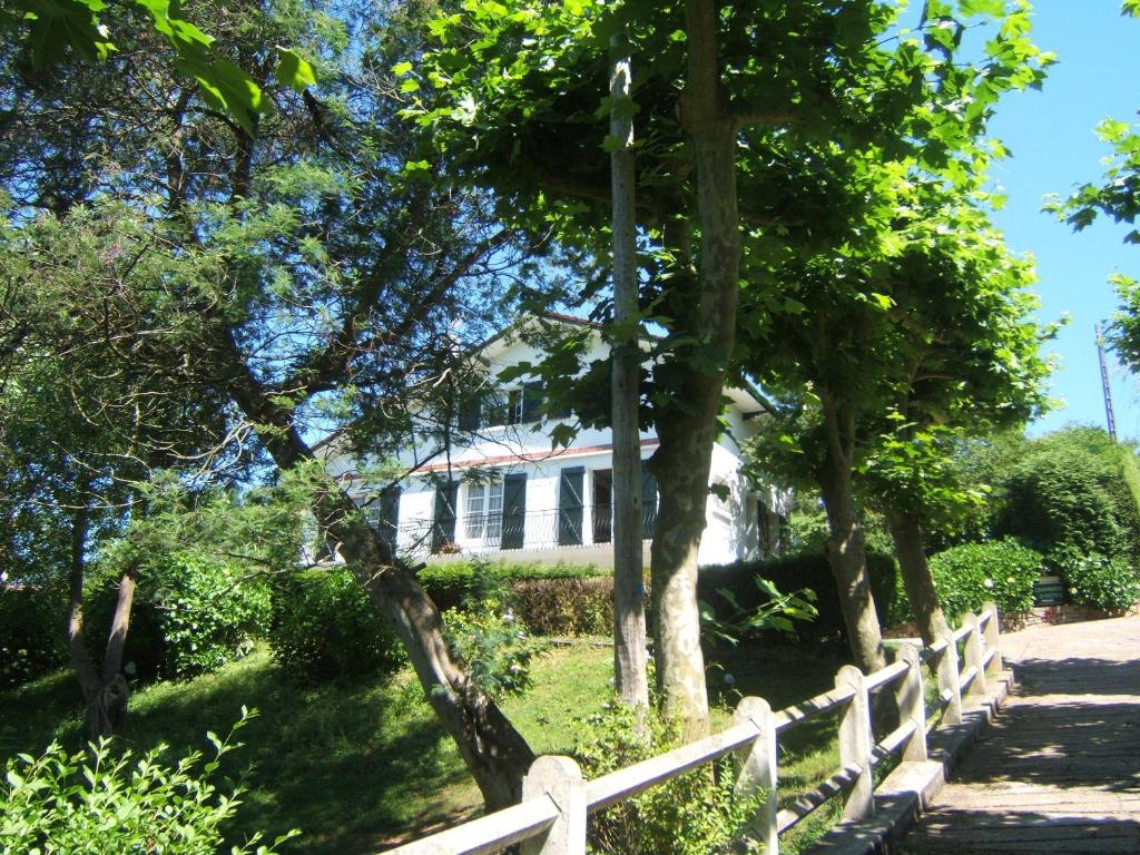 una casa blanca con una valla y árboles en Villa Gypsie, en Urrugne