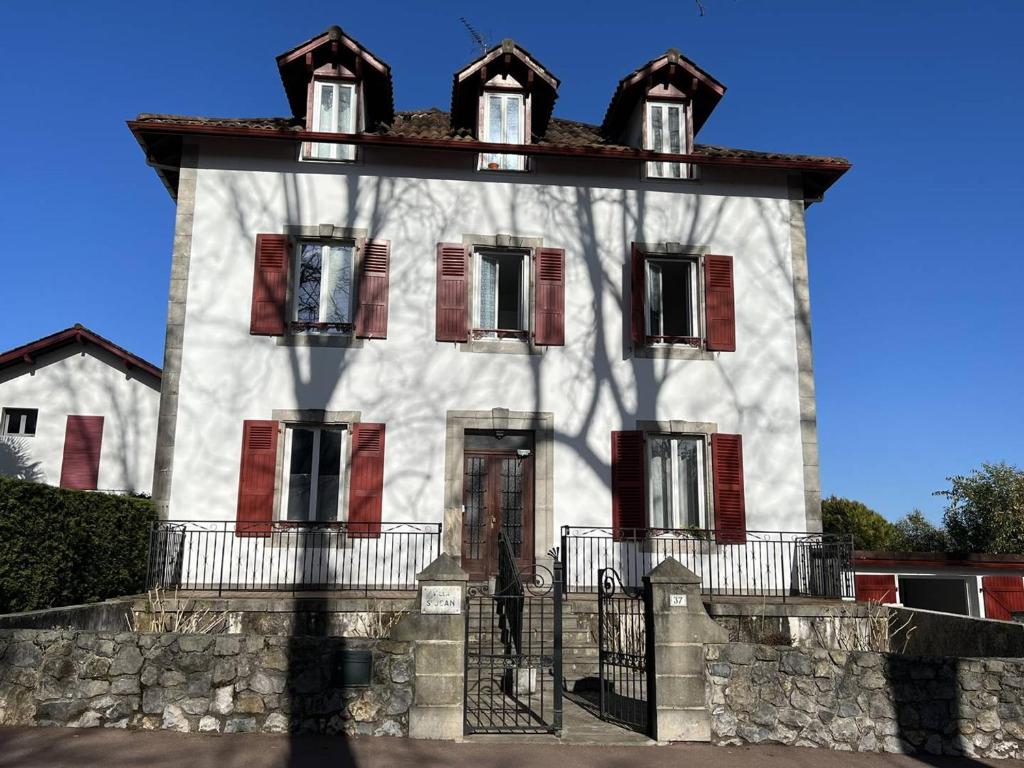 a large white building with red shuttered windows at Studio Cambo-les-Bains, 1 pièce, 2 personnes - FR-1-495-10 in Cambo-les-Bains