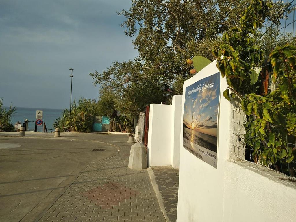 uma cerca branca com um cartaz ao lado de uma rua em La Grazia em Parghelia